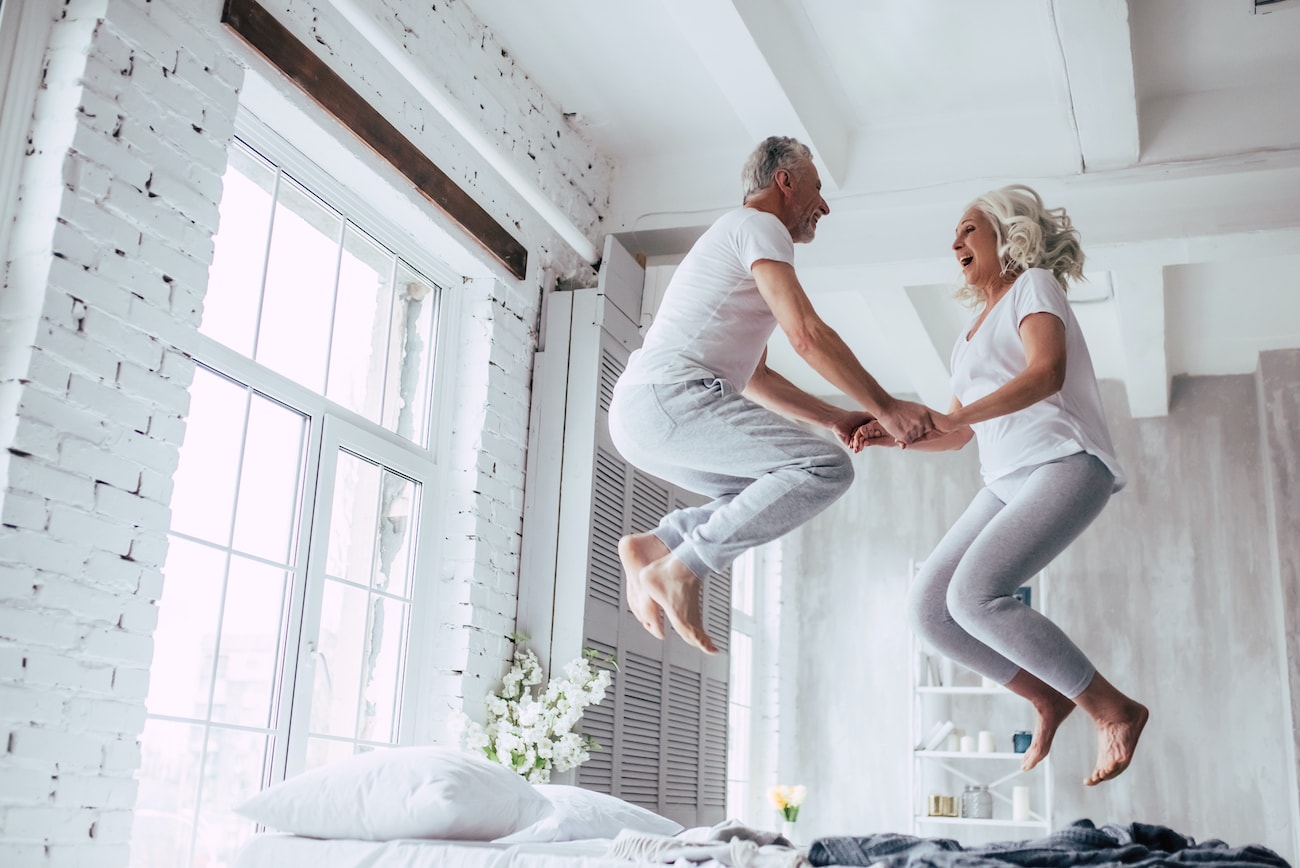 Altes Paar springt auf dem Bett